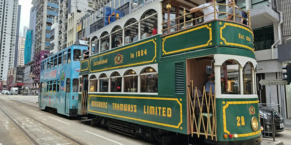 Eine alte grün-goldene Doppeldecker-Straßenbahn in einer Straße in Hongkong