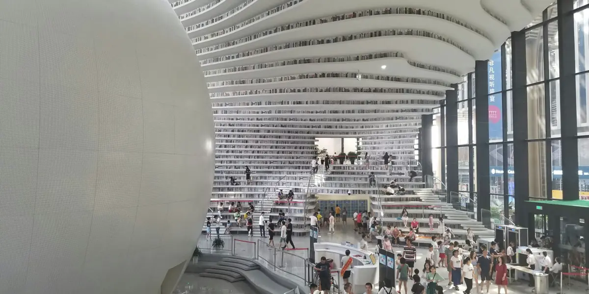 L'interno della biblioteca di Binhai, a Tianjin, con scaffali curvi e una grande sfera bianca