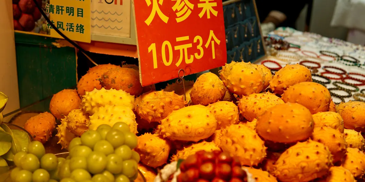 Banco di frutta con un cartello che dice 10元3个: tre per 10 yuan